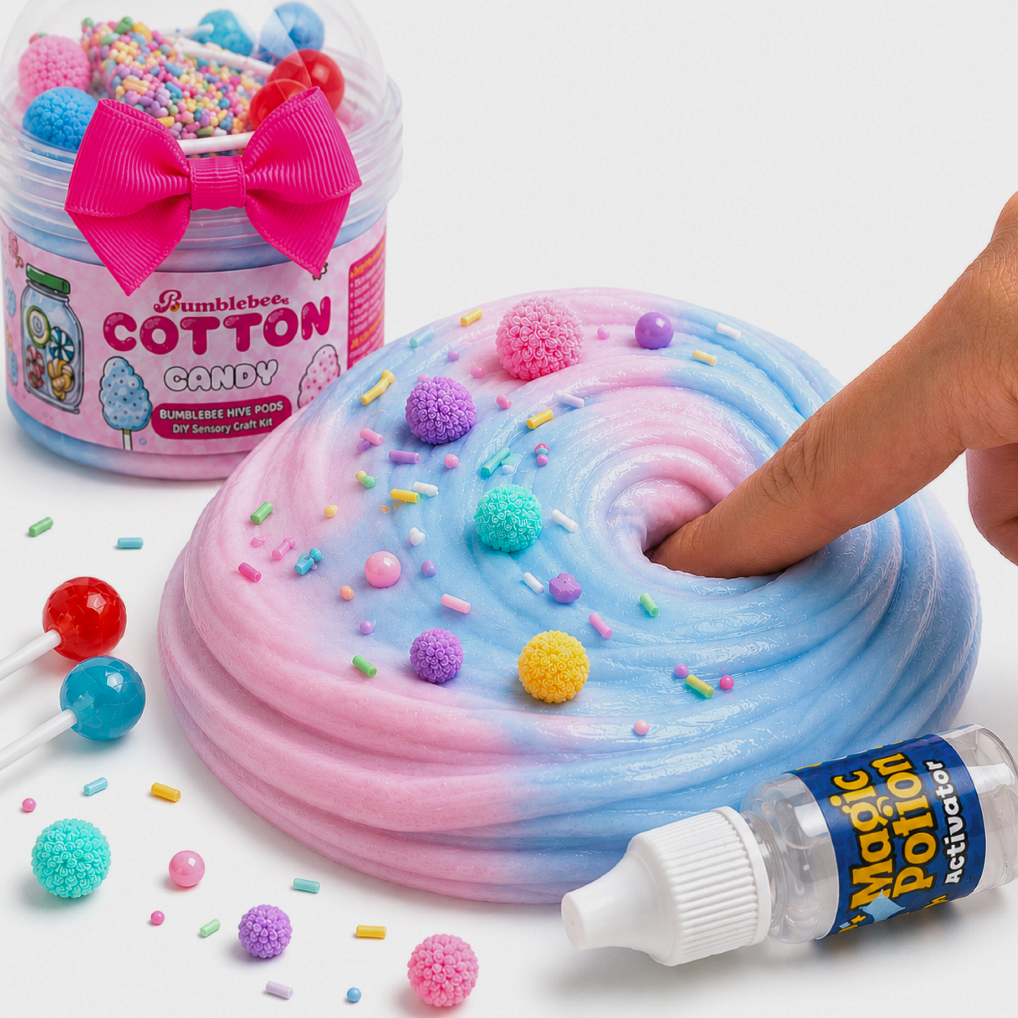 Finger pressing into pink and blue Cotton Candy butter slime topped with colourful pom-poms and sprinkles