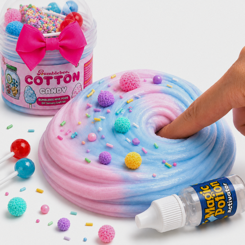 Finger pressing into pink and blue Cotton Candy butter slime topped with colourful pom-poms and sprinkles