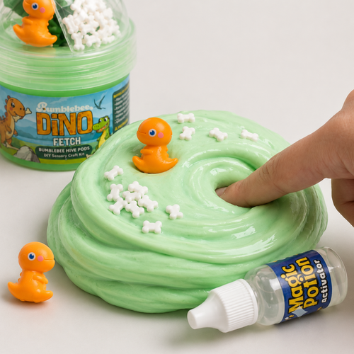 Finger pressing into green Dino Fetch slime topped with bone-shaped sprinkles and an orange dinosaur charm